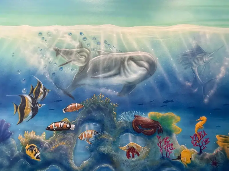 Hand-painted undersea mural of dolphins, coral and tropical fish at Preferred Pediatrics in Thibodaux